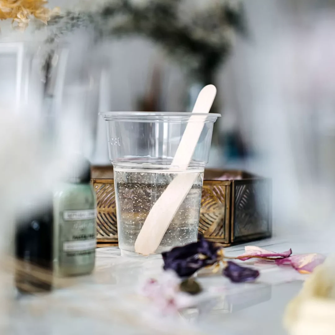 Resin mixing in a clear plastic cup with wooden stir stick,